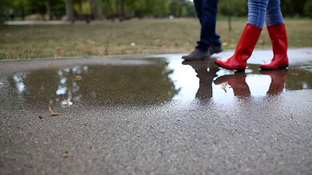 橡胶靴正跳进水坑里溅起水花。视频素材