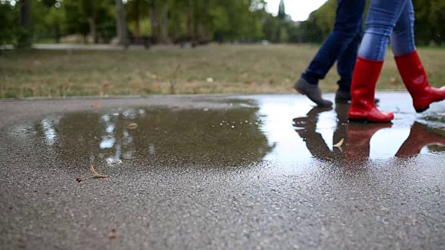 橡胶靴正跳进水坑里溅起水花。视频素材