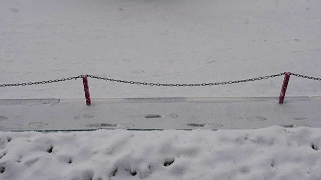 雪慢慢地落在人行道上，冬天的道路在下雪视频素材