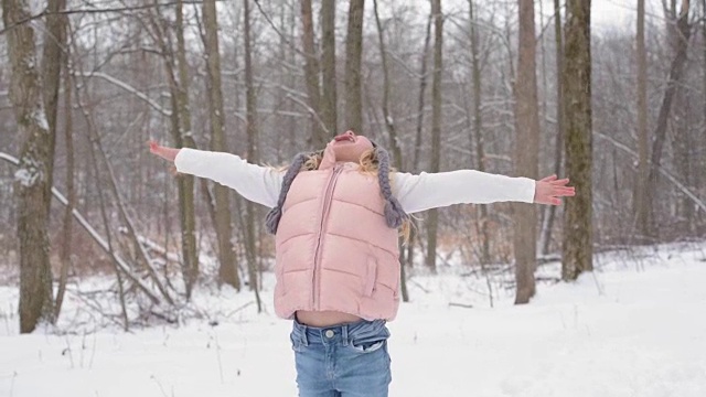 年轻的女孩在白雪覆盖的小径上捕捉雪花视频素材