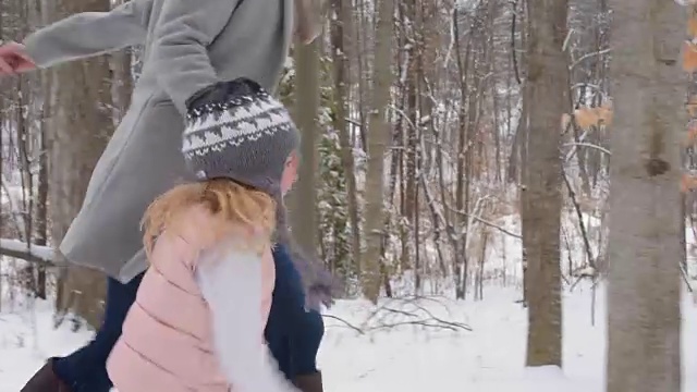 母亲和女儿在一条被雪覆盖的小径上奔跑视频素材