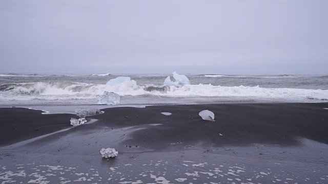 在冰岛的黑沙滩上，海浪拍打着冰山视频素材