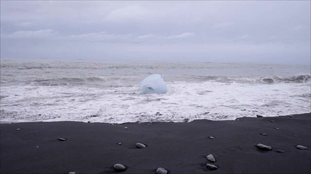 在Jokulsarlon Diamond的海滩上，海浪拍打在冰岛黑沙滩上的冰山的慢动作视频视频素材