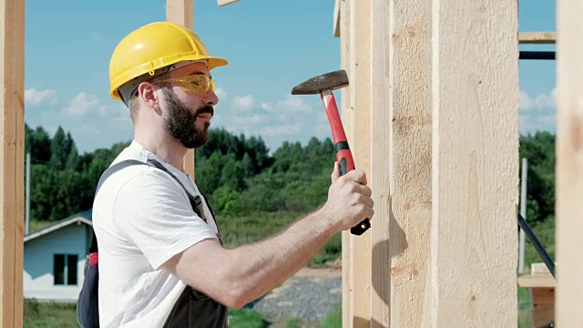 这个人是一个在木框架房子屋顶上的建筑工人。视频素材