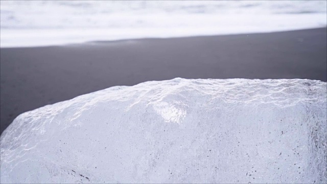 在Jokulsarlon Diamond的海滩上，海浪拍打在冰岛黑沙滩上的冰山的慢动作视频视频素材