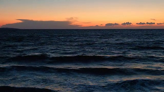 海滩上的日落。平静的田园诗般的景色，金色的日落在海面上，海浪慢慢地溅起水花视频素材