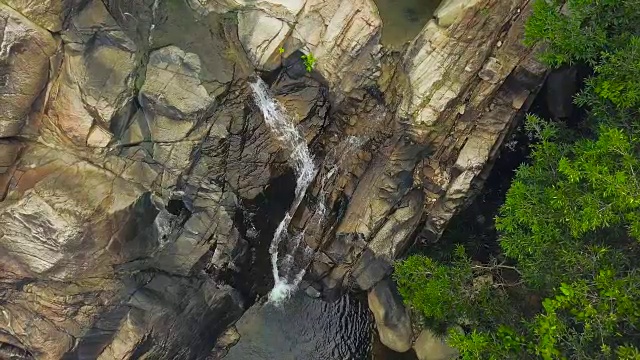 山河在雨林鸟瞰图上的岩石瀑布上流动。山顶瀑布和石质河流流动在热带森林视频素材