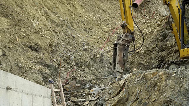 在建筑工地的采石场里，挖掘机上的大风动锤敲击岩石。视频素材