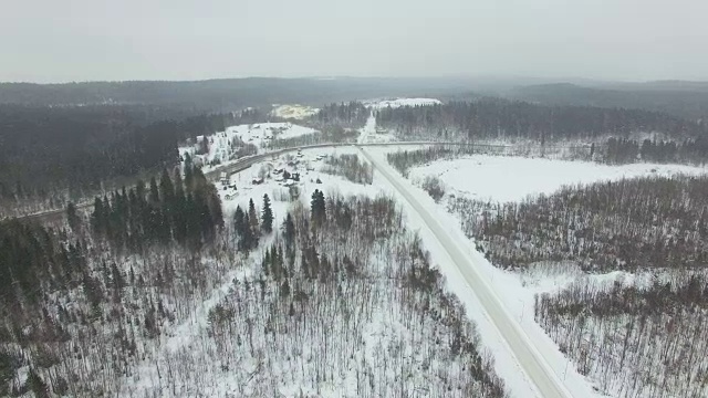 在大雪纷飞的冬天，飞过乡村公路穿过森林。视频素材