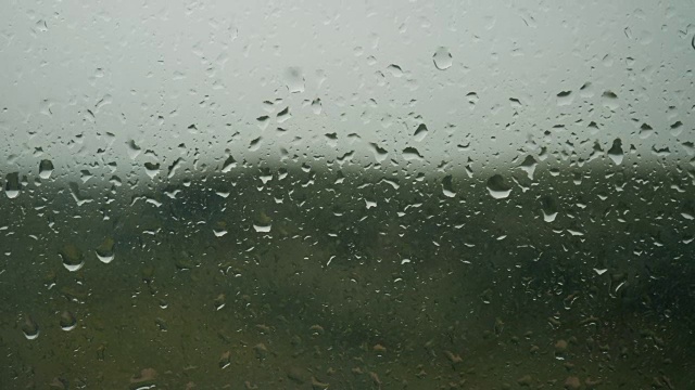 雨滴出现在窗户玻璃上，雨开始，水滴的背景视频素材