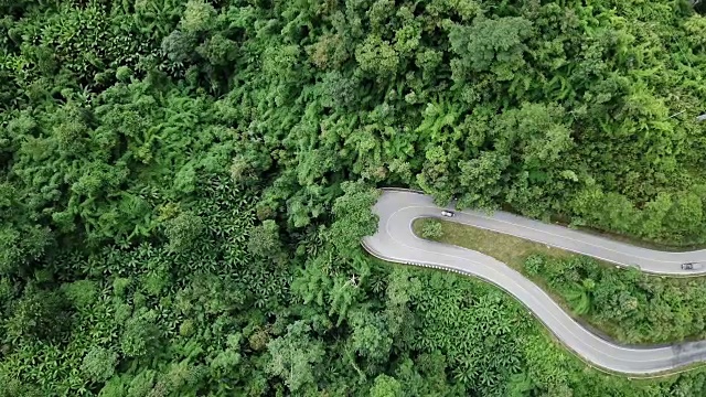 鸟瞰图蜿蜒的道路在森林和汽车驾驶，安全驾驶的概念视频素材