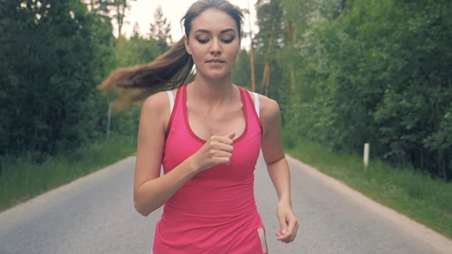 一个漂亮女士沿着小巷慢跑的慢镜头。健康苗条的年轻女运动员跑步。视频素材