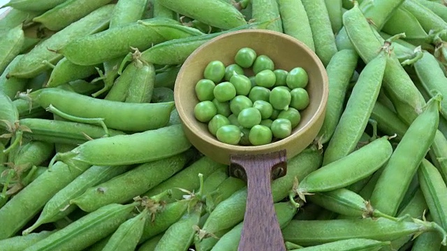 旋转的绿色豌豆荚和木勺豌豆视频素材