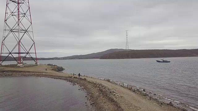 鸟瞰图渔船在海上航行经过电力毛巾和岸上的人视频素材