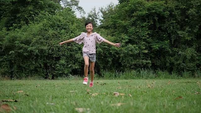 慢镜头，快乐的小女孩在公园里跑步微笑视频素材