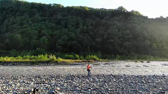 无人机镜头的摄影师旅行和拍照。地点:山区河流。摄影师用专业相机拍摄自然视频下载