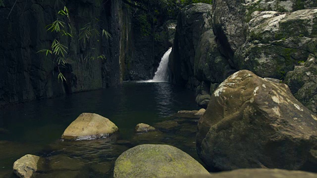 雨林中的高山瀑布。从瀑布中流下的水在河中的巨石上流动视频素材