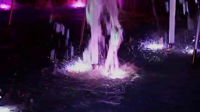 五彩缤纷的音乐喷泉在夜晚，闪烁着不同的色彩视频素材