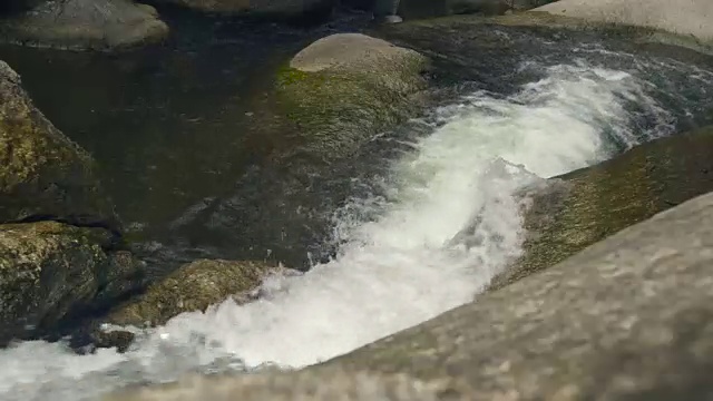 热带森林中的山间河流。从瀑布中流过的河水流过大石头视频素材