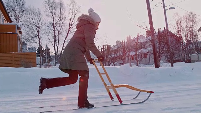 SLO MO女人用踢式雪橇在雪地上滑行视频素材