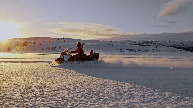 SLO MO在夕阳下骑着雪地摩托视频素材