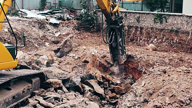 一个重型建筑行业的挖掘机在建筑工地粉碎石头的特写视频素材