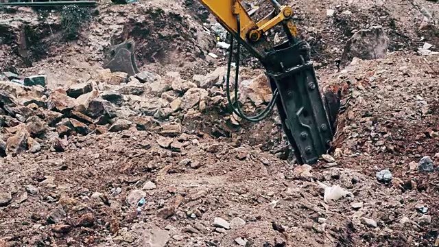 一个重型建筑行业的挖掘机在建筑工地粉碎石头的特写视频素材