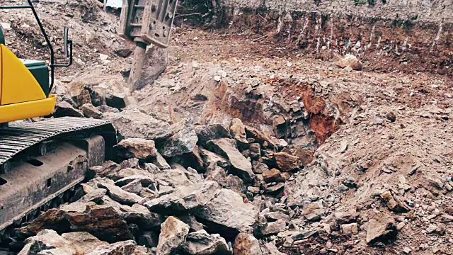 一个重型建筑行业的挖掘机在建筑工地粉碎石头的特写视频素材