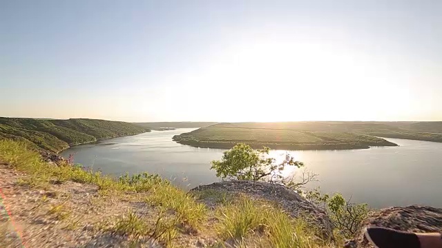 一对相爱的情侣坐在河边。夕阳光视频素材