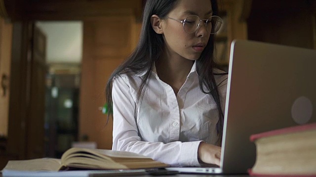 美丽的女亚洲学生生物学家在眼镜看书视频素材