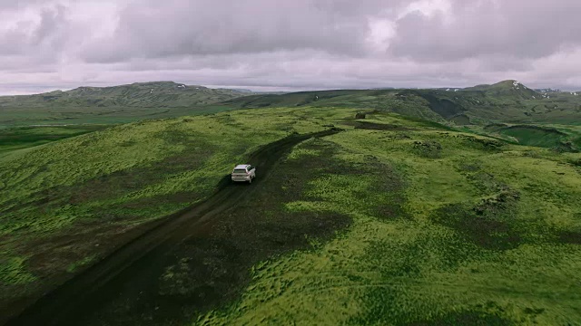 空中跟踪拍摄的银色4x4越野车行驶在山顶的山路视频素材