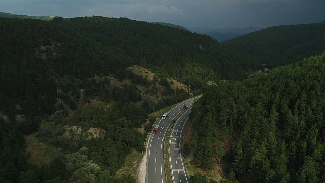 航拍的公路之间的树木在森林与黑暗的天空视频素材