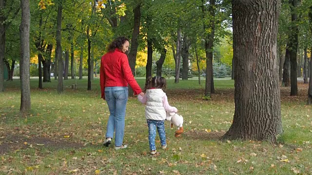 一位妇女和她的孩子在秋天的公园里散步视频素材