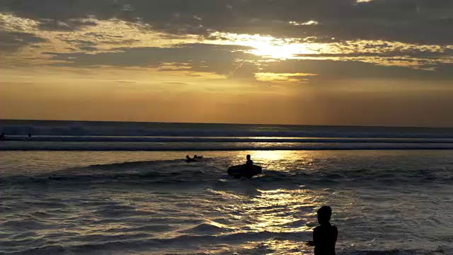 日落时分，长板冲浪者在巴厘岛库塔海滩上散步冲浪视频素材