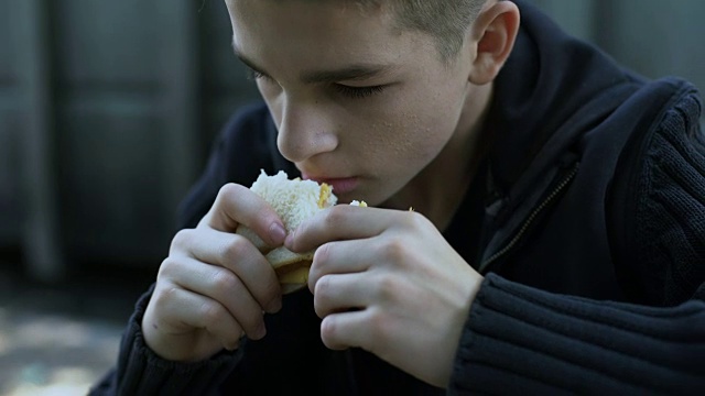 饥饿的少年吃着便宜的不健康的三明治，劣质的儿童餐视频素材