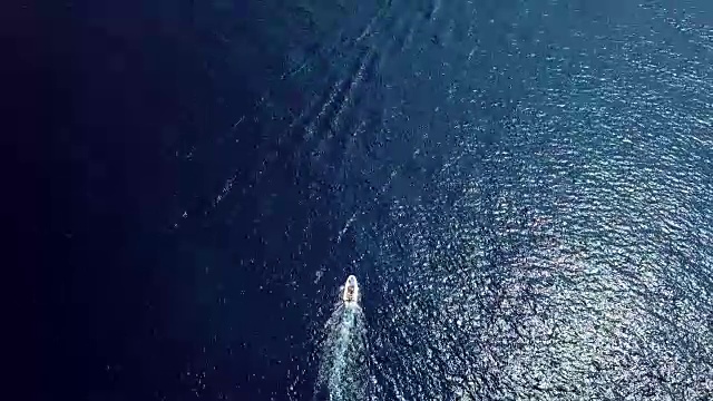 从上面的视频中，鸟瞰一艘载有游客的橡皮船在透明的绿松石海上航行。意大利撒丁岛。视频素材