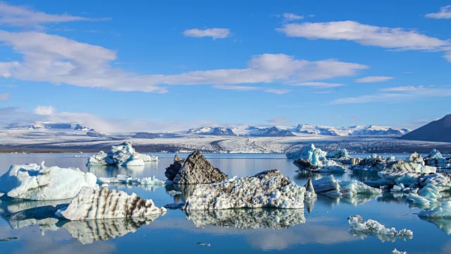 4k时间流逝云移动与蓝色冰山漂浮在冰岛Jokulsarlon冰川泻湖视频素材