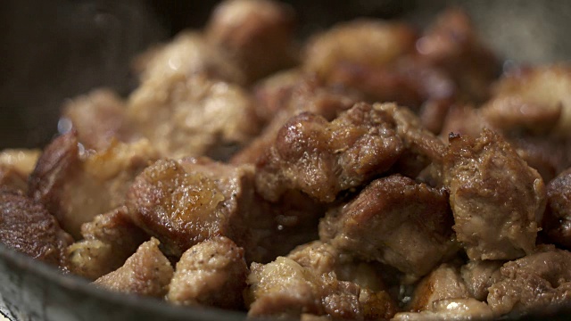 烹饪香酥炸猪肉。在加热的铁煎锅里炸肉片的特写视频素材