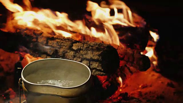 营火上的水壶正沸腾着。为徒步旅行准备热茶和食物视频素材