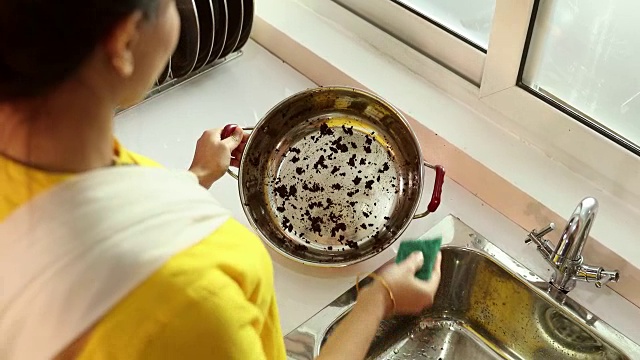 印度德里，一名年轻女子在厨房水槽里用清洁海绵洗锅视频素材