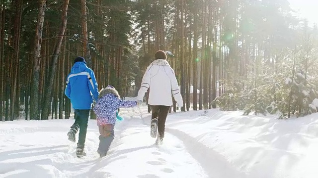 一位妇女带着两个孩子走在森林里一条被雪覆盖的小路上视频素材