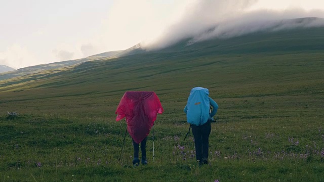 游客行走在草甸上，以山谷和云雾山峰为背景视频素材