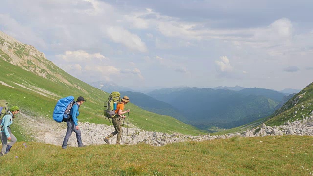 徒步旅行的人在山在绿色的山丘和天空的背景。视频素材