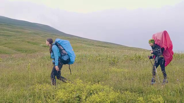 旅行的女人背着双肩包走在绿色的山丘上视频素材