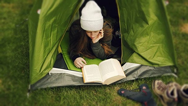 露营活动。一个女人在帐篷里看书视频素材