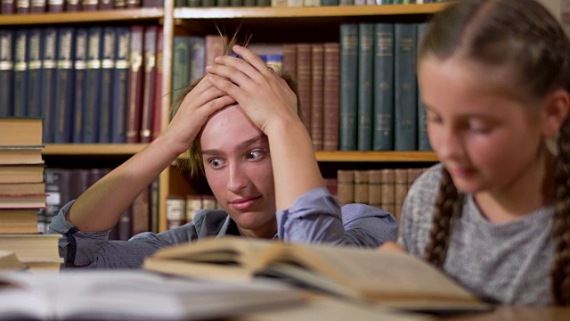 一个英俊的男孩和一个可爱的小女孩正坐在图书馆的一张桌子旁视频素材