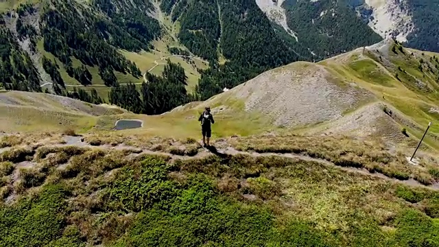 在蓝色天空下的落基山上行走的男性徒步者视频4K视频素材