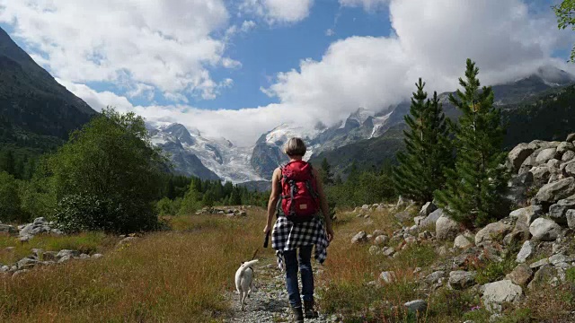 女人和狗在瑞士Morteratsch山谷徒步旅行视频素材