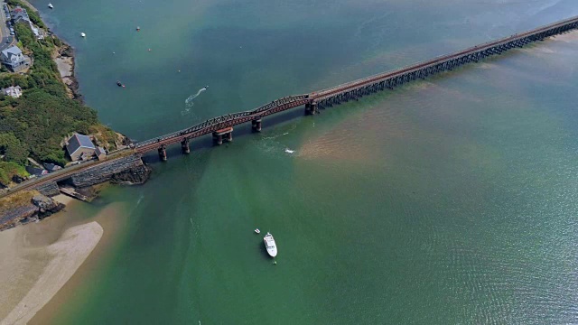 鸟瞰图，放大和缩小移动。无人机在上升的潮汐海流，抛锚的船，铁路大桥在巴茅斯，威尔士视频素材