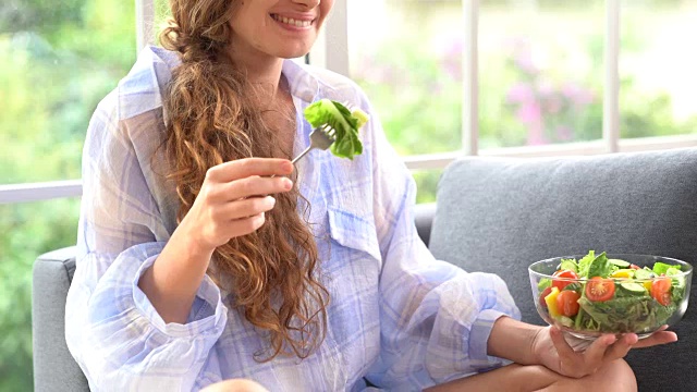 一个吃沙拉用药片的漂亮年轻女人视频素材